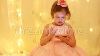 小女孩玩智能手机。 宝贝公主在手机上看视频的背景下亮着灯。